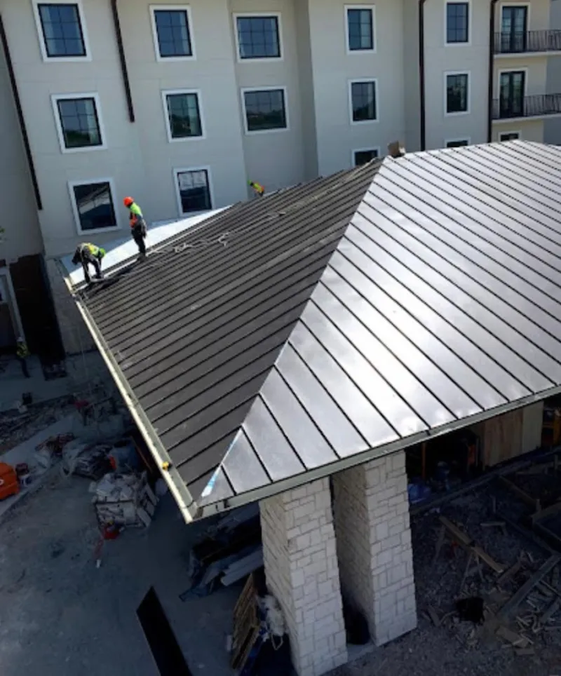 Crew installing standing seam metal roof panels on a commercial project in Raleigh Hills